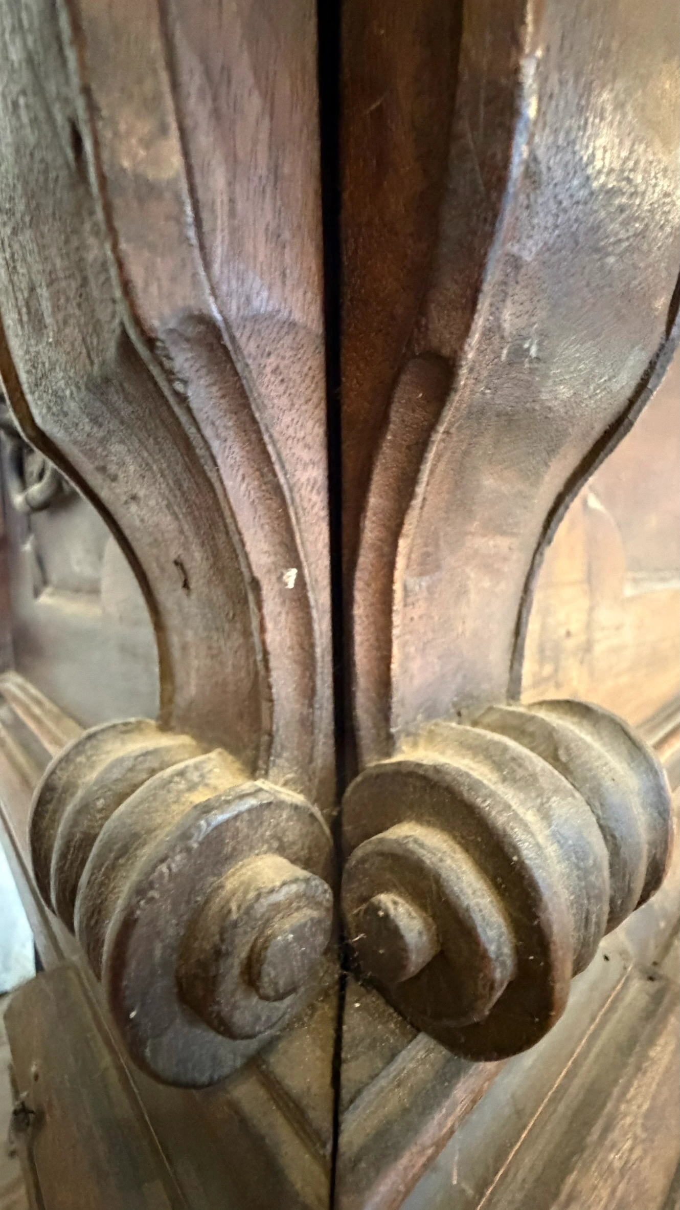 Detail of lower corner consoles with tightly carved volute scrolls and moulded base junction.