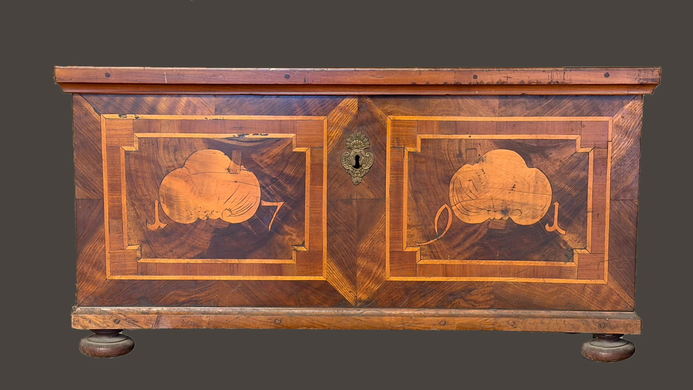 Intarsierte Truhe von 1791 mit geometrischen Marketeriefeldern, zentralen Kartuschen und Messing-Schlüsselschild.