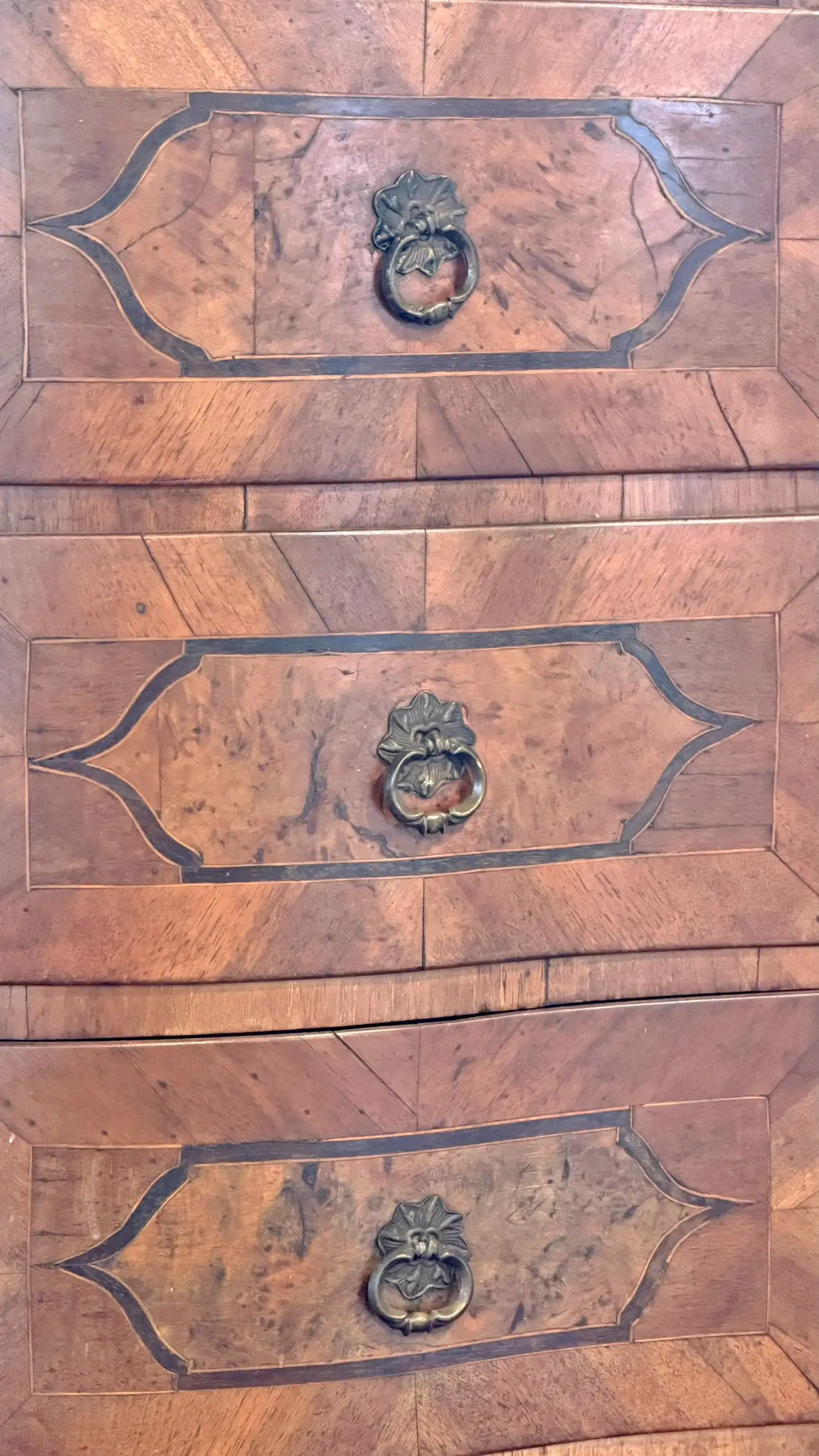 Detail der bombierten Schubladen mit Marketeriefurnieren und Messingfallgriffen.